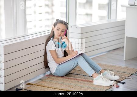 Long-haired girl in white tshirt sitting on the floor Stock Photo