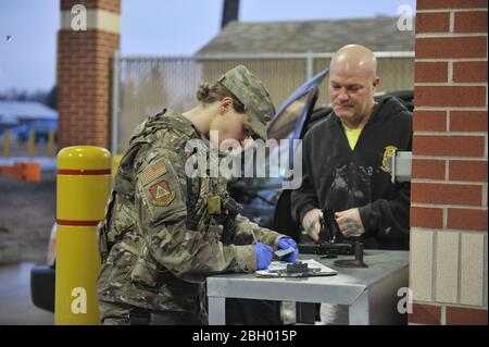 Master Sgt. Ariel McVicker, a security forces squadron augmentee assigned to the Ohio National Guard’s 180th Fighter Wing, wears protective gloves while validating credentials of a contractor arriving at the installation, March 17, 2020. The 180FW implemented local Force Health Protection measures in an effort to safeguard military and civilian personnel and to help prevent wide-spread of COVID-19 in Northwest, Ohio. Air National Guard photo by Senior Master Sgt. Beth Holliker. Stock Photo