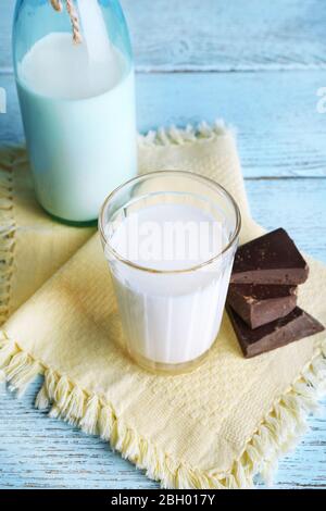 Glass and bottle of milk with chocolate chunks on color wooden planks background Stock Photo