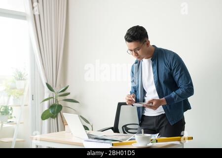 Profile shot of a young male architect working on blueprints at his desk at the office copyspace building plans construction project engineer expert s Stock Photo