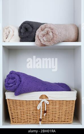 Rolled towels with wicker basket on shelf of rack background Stock Photo