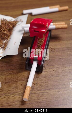 Rolling machine, cigarettes and tobacco on table Stock Photo