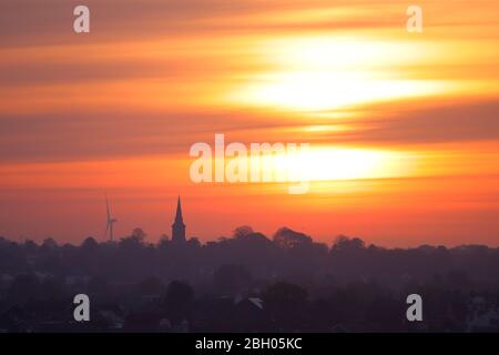 A beautiful sunrise over Garforth in Leeds. Hook Moor Wind Farm & St Mary's church stand out above the horizon Stock Photo