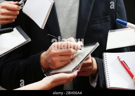 Elegant man signing autograph in notebook on dark background Stock Photo