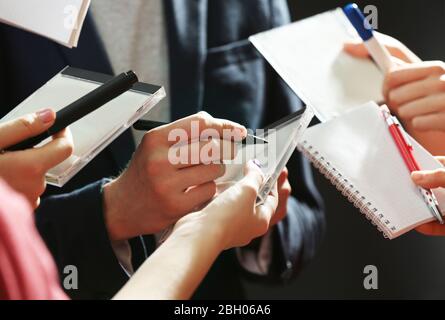 Elegant man signing autograph in notebook on dark background Stock Photo