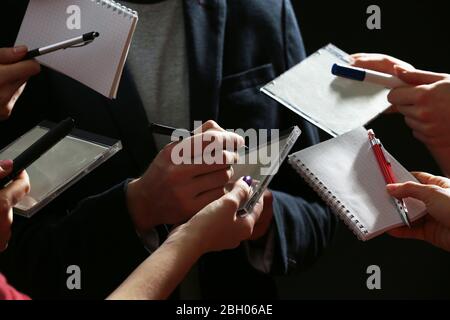 Elegant man signing autograph in notebook on dark background Stock Photo