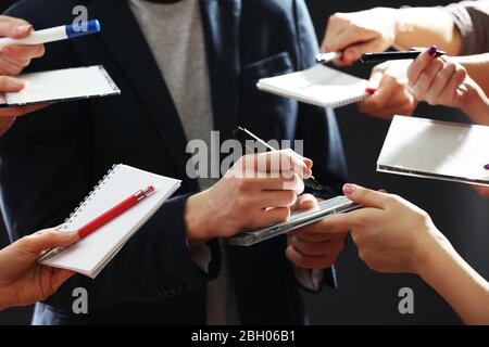 Elegant man signing autograph in notebook on dark background Stock Photo