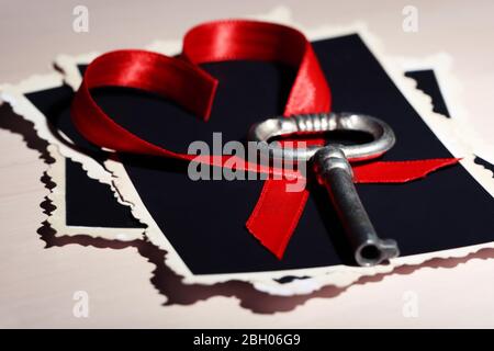 Retro key with photos and heart on wooden table background Stock Photo