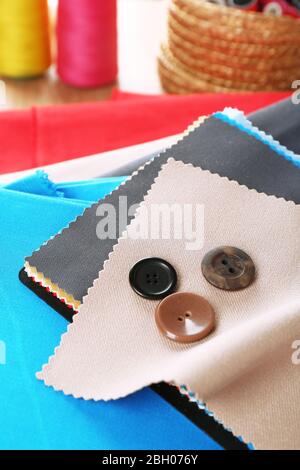 Colorful fabric samples with buttons and threads on wooden table background Stock Photo