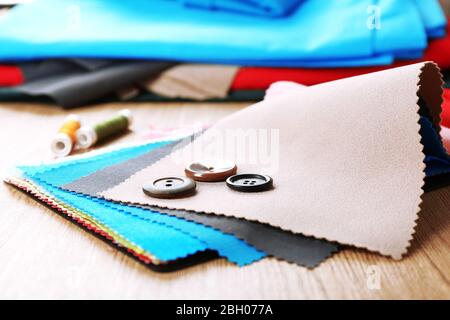 Colorful fabric samples with buttons and threads on wooden table background Stock Photo
