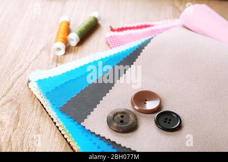 Colorful fabric samples with buttons and threads on wooden table background Stock Photo