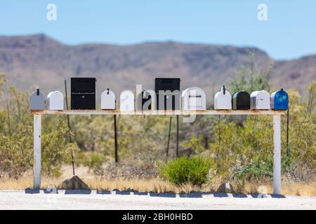 Symmetrical close up of a row of iconic traditional American letterboxes, against a desertic landscape