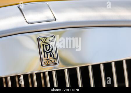 Iconic close up of the chrome brand name and radiator grille of a yellow Rolls Royce car Stock Photo