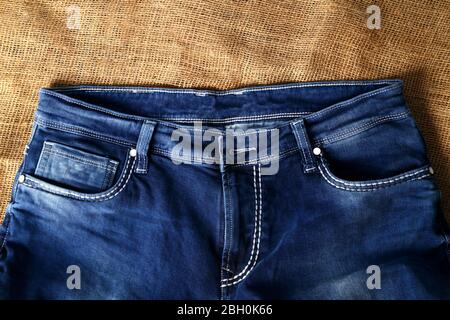 Old Blue jeans fashion design On brown hemp sack texture background,.Ripped jeans of a stack Hipster fashion copy space for text commentary . Stock Photo