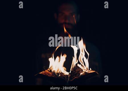 Man holds burning book in his hands. Stock Photo