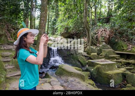 Young thai woman taking photos with beautiful nature park after quarantine home stay. Stock Photo