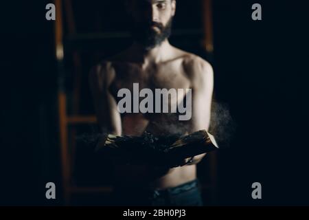 Man holds burning book in his hands. Stock Photo