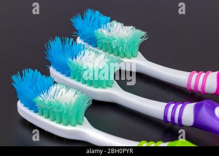 Old unusable worn-out and must change colorful toothbrushes on black background Stock Photo
