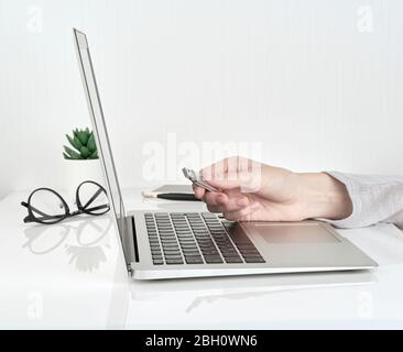 Person opening usb flash next to laptop, Office Work concept on white wall background Stock Photo