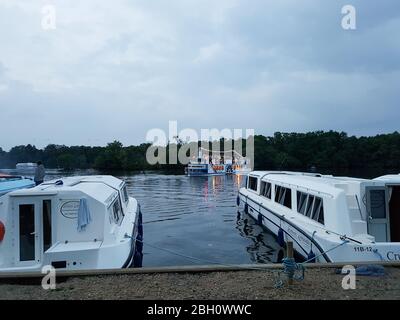 Holiday boats moored up at Salhouse broad on the Norfolk Broads with the Queen of the broads in the background Stock Photo