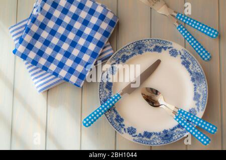 Empty plate, silverware and towel over wooden table background. View from above, blue color Stock Photo