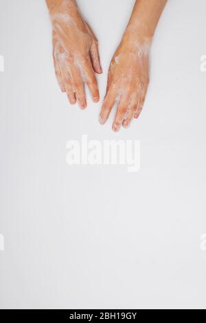 Feminime hands with soapy bubbly foam on white background. Stock Photo