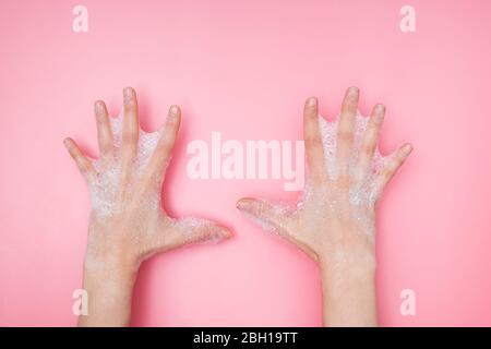 Feminime hands with soapy bubbly foam on pink background, Stock Photo