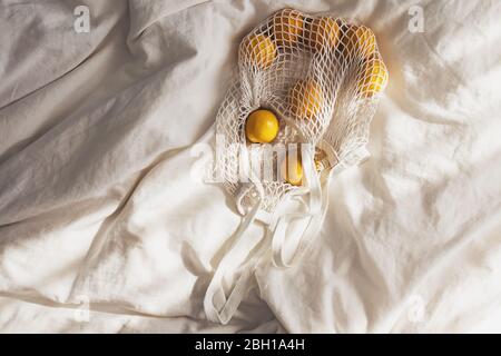 Cotton bag with lemons lying on the bed. Stock Photo