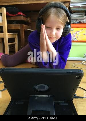 Twickenham, London, UK. 23 Apr, 2020. Year 5 class pupil praying child / kid aged 10 years old takes part in the opening prayer during first trial of a ‘Zoom' virtual school morning assembly. Like all schools, Saint Richard Reynolds Catholic College (SRRCC) is in lockdown due to the current COVID-19 Coronavirus pandemic. (stockmo) Stock Photo