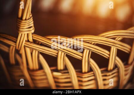 A beautiful wicker rustic basket made from natural materials, made by hand, is illuminated by warm summer sunlight. Stock Photo