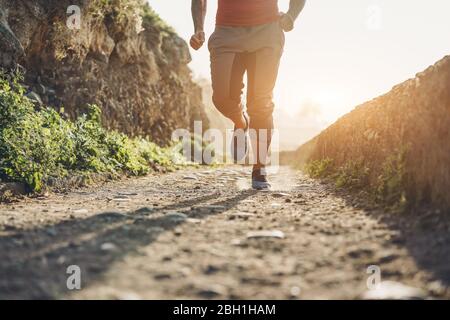 Fit tattoo man doing jogging session alone during Coronavirus quarantine  - Workout and fitness lifestyle concept - Focus on feet Stock Photo