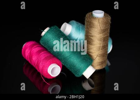 Group of four whole thread spools isolated on black glass Stock Photo