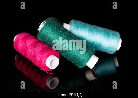 Group of three whole thread spools isolated on black glass Stock Photo