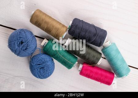 Lot of whole colourful thread spools on white wood Stock Photo