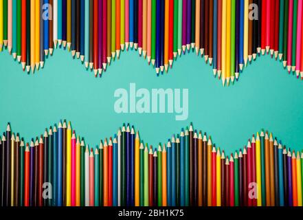 Colorful pencils arranged in a wave isolated over blue background Stock Photo