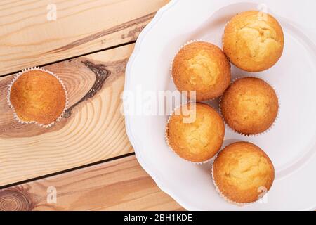 Group of six whole small baked muffin on porcelain plate on wood Stock Photo