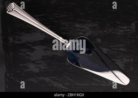 One whole steel silver cake server isolated on black glass Stock Photo