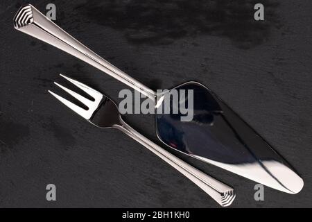 Steel silver cake server and dessert fork isolated on black glass Stock Photo