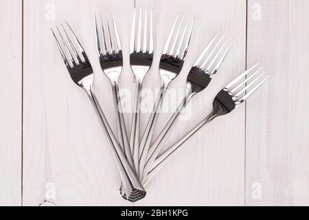 Group of six whole steel fork on white wood Stock Photo