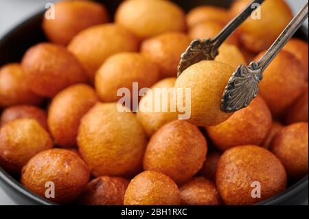 Loukoumades or luqaimat or lokma in black bowl. Loukoumades is an eastern cuisine donunts popular during Ramazan. Popular Ramadan Food. Iftar and Suhu Stock Photo