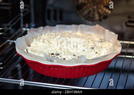 raw dough for cottage cheese casserole in a round ceramic form in the oven. Stock Photo