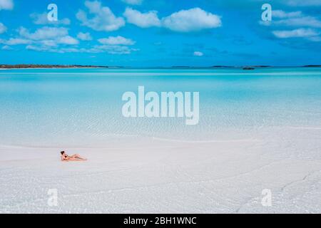 Woman sunbathung on white sand bank in the sea, Bahamas, Carribean Stock Photo