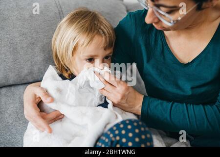 Mother blowing little daughter's nose Stock Photo
