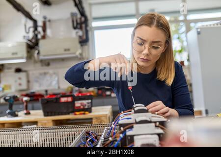 Female electrician working on circuitry in workshop Stock Photo