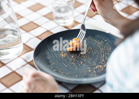 Woman eating last pasta from plate Stock Photo