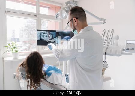 Young woman getting dental treatment in clinic, doctor explaining x-ray Stock Photo