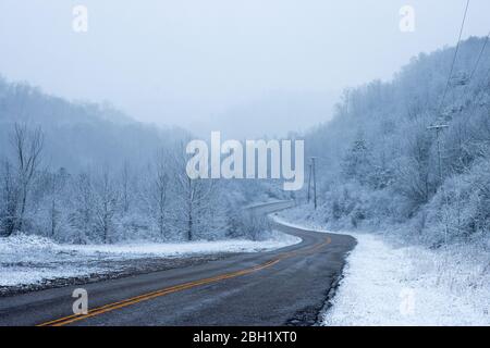 A rural, mountainous road winds through the Appalachian foothills of Eastern Kentucky in winter. Stock Photo