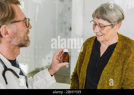 Doctor recommending pills in bottle to senior patient Stock Photo