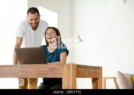 Happy couple working at laptop from home in home office in modern living room Stock Photo