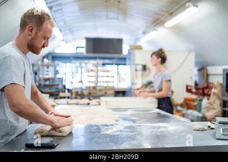 Man and woman preparing bread in bakery Stock Photo